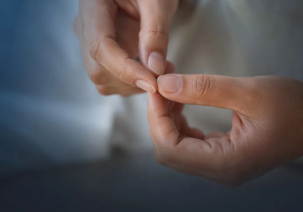 一张温暖且专业的医学摄影横版头图。画面特写了一只手正在柔和的暖光下,仔细而温柔地观察另一只手的指甲和指尖细节,呼应文中“关注肢端”的自检行为。色调以暖灰色和品牌蓝(#1996DF)为主,充满人文关怀。画面下方三分之一处为简洁的深色渐变留白,不含任何文字,方便叠加标题。